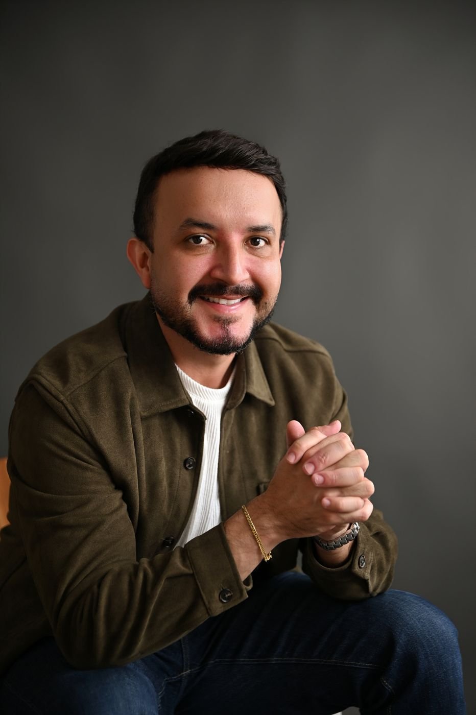 Dr. Fábio Baquero sentado, com as mãos entrelaçadas, sorrindo
