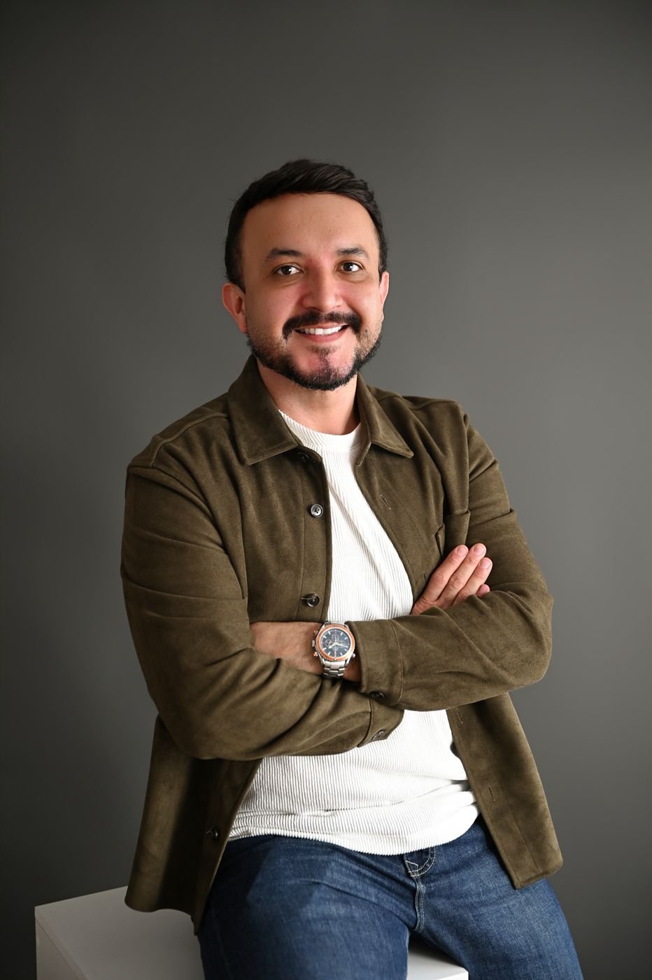 Dr. Fábio Baquero sorrindo, de braços cruzados, com jaqueta marrom